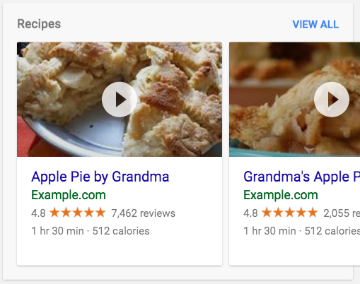 Carrusel de recetas en los resultados de búsqueda. El carrusel muestra dos tarjetas sobre diferentes tipos de pasteles. Puedes hacer clic en los resultados para reproducir un vídeo.